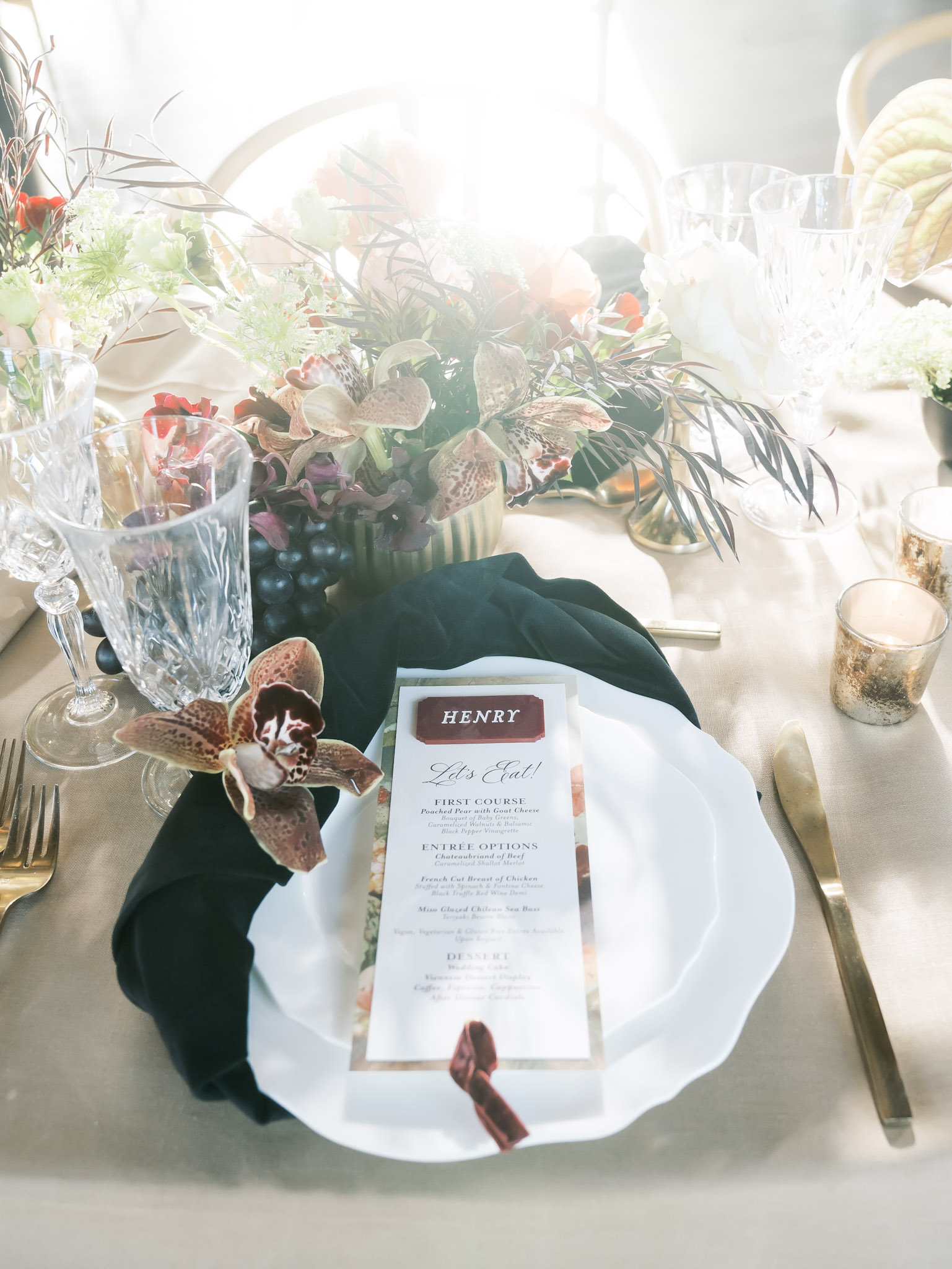 Elegant place setting with personalized menu card, floral arrangements, and crystal glasses