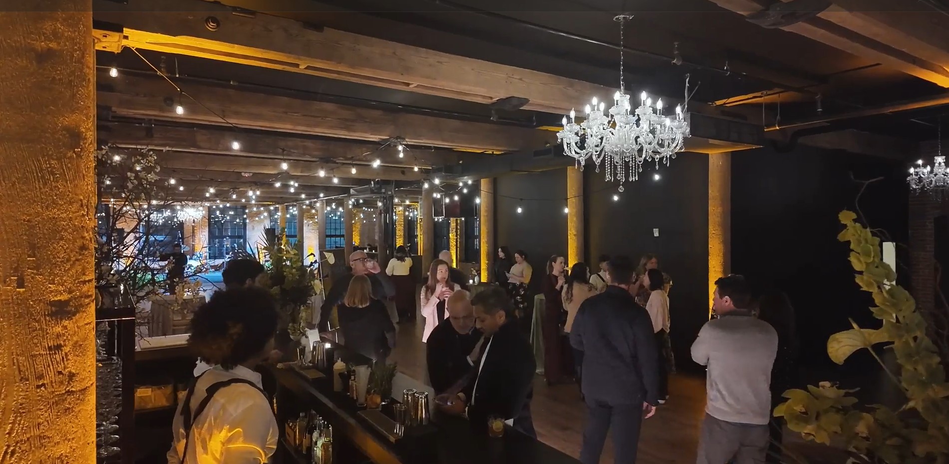 Wide shot of event space with guests and crystal chandeliers