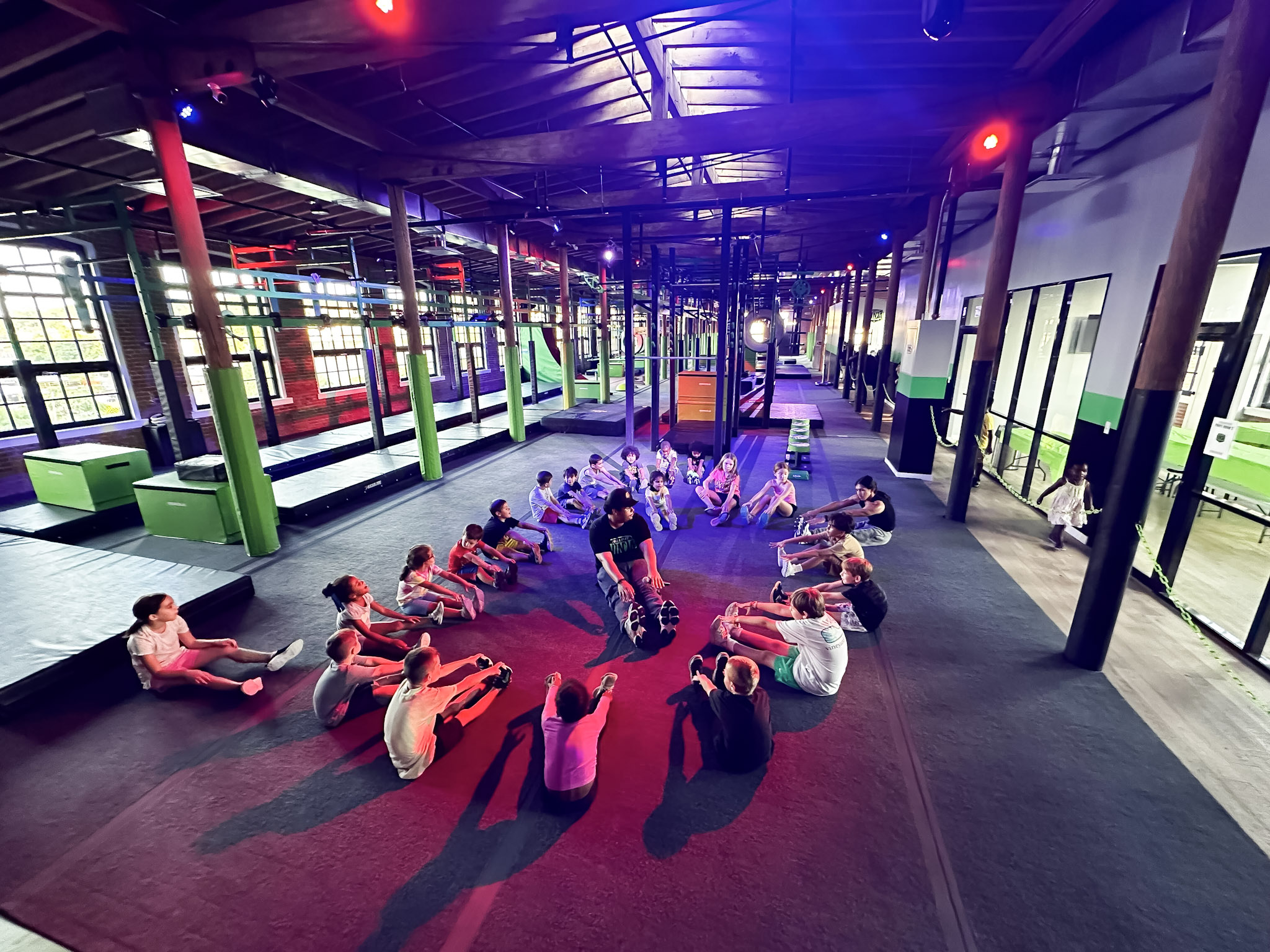 Kids stretching in a circle with a coach at No Limit Ninja